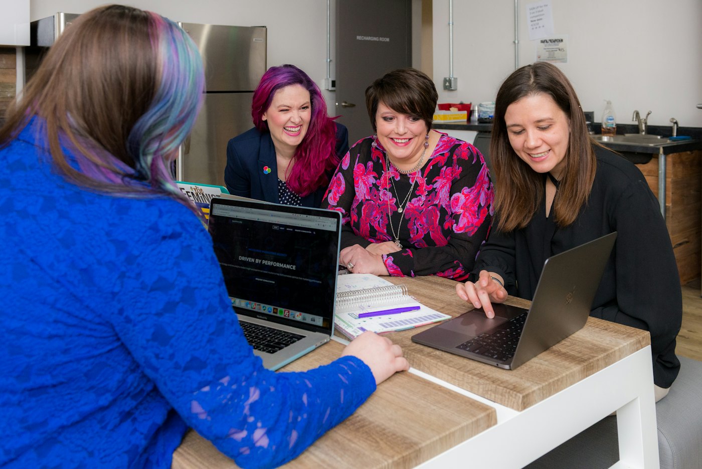 Four women working together around laptops at a table